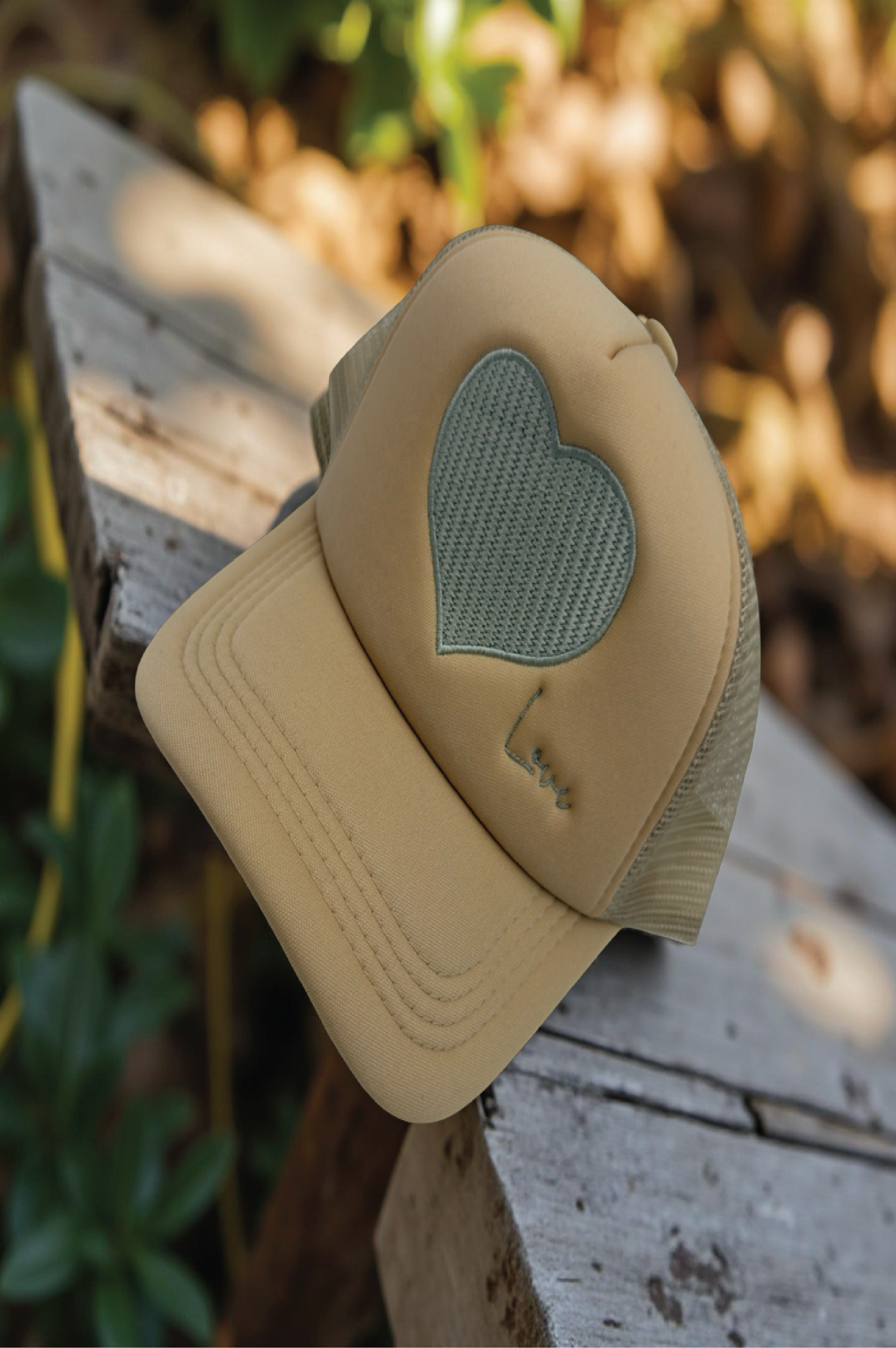 Beige cap with a heart-shaped patch on a wooden surface