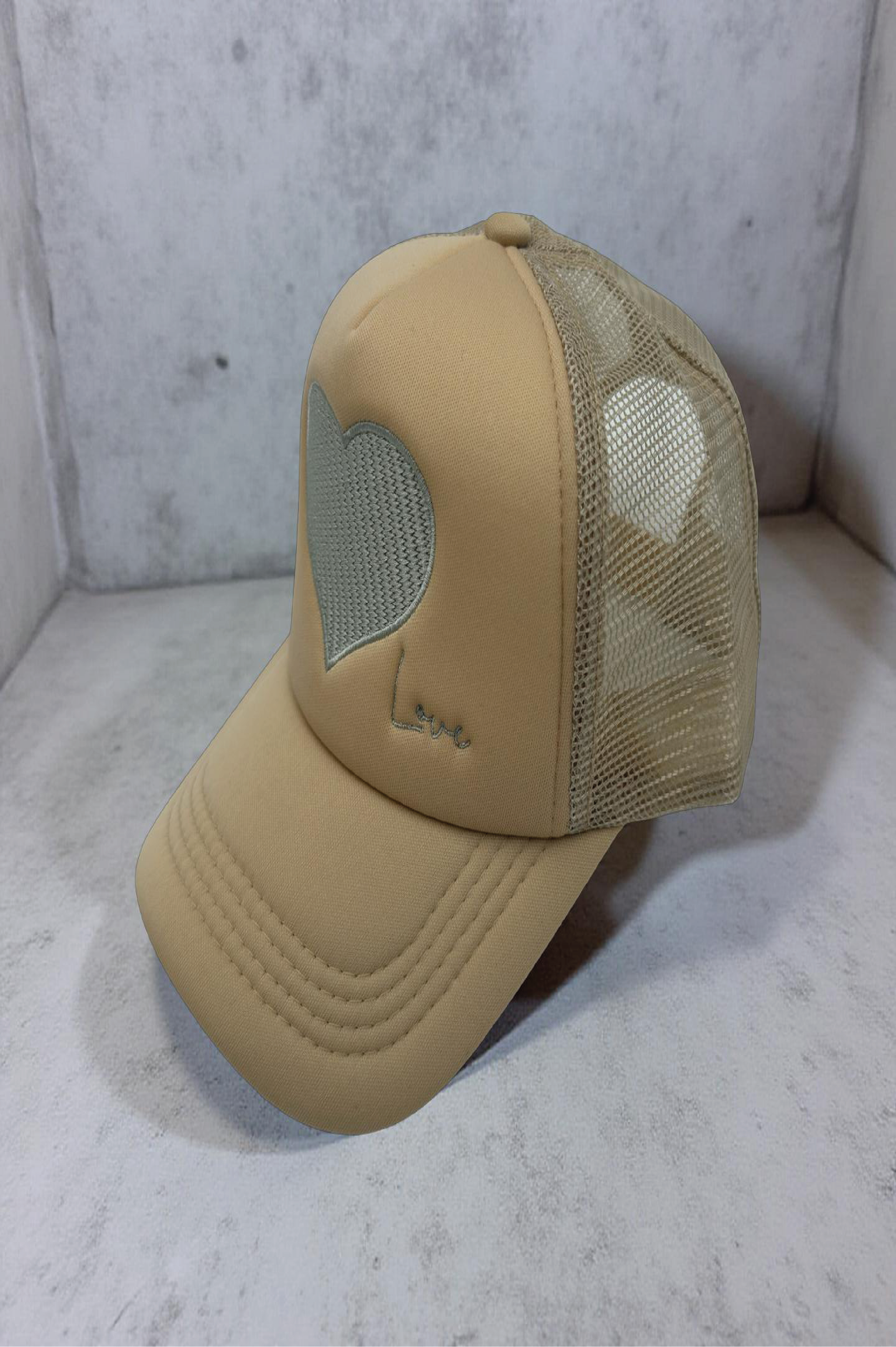 Beige trucker cap with mesh back on a light gray surface
