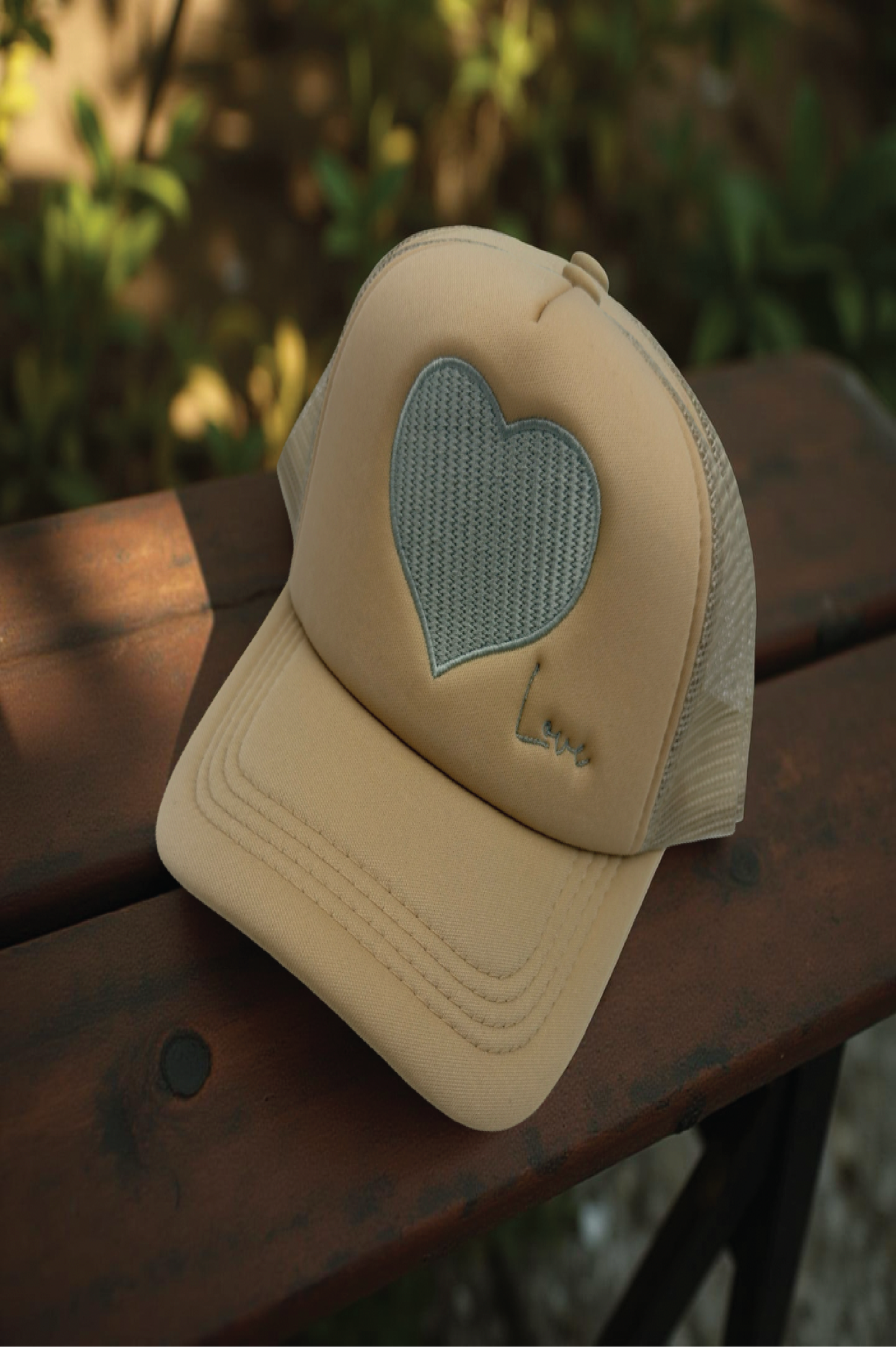 Beige cap with a heart-shaped cutout on a wooden surface with a blurred natural background