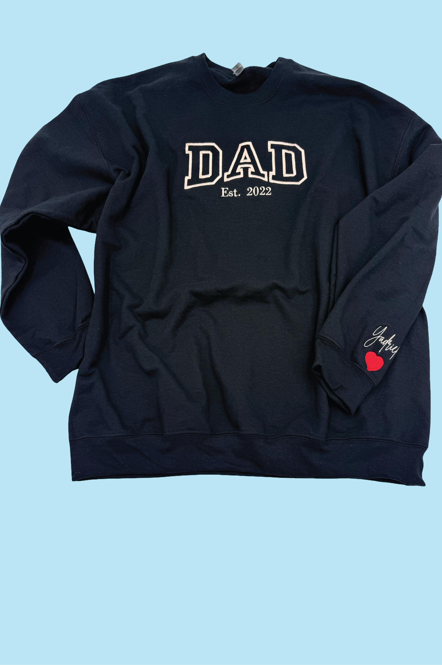 Black sweatshirt with 'DAD Est. 2022' text on a light blue background

Dad custom embroidered sweatshirt with kids’ names on sleeve – black pullover

Personalized dad sweatshirt with child name embroidered on sleeve – gray crewneck