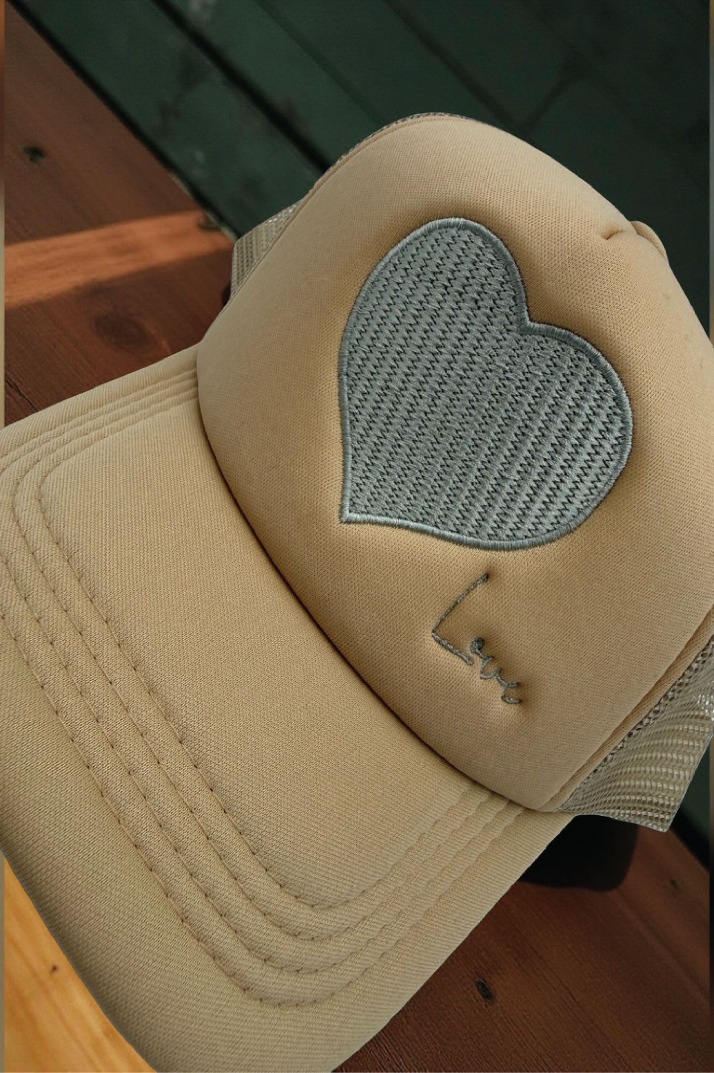 Beige cap with a heart-shaped patch on a wooden surface