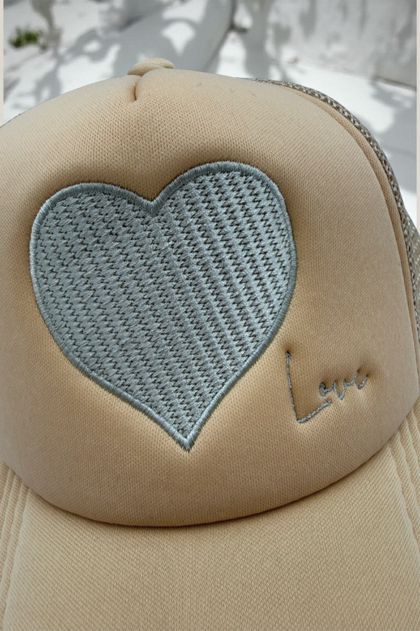 Beige cap with a heart-shaped patch and 'Love' embroidery on a light background