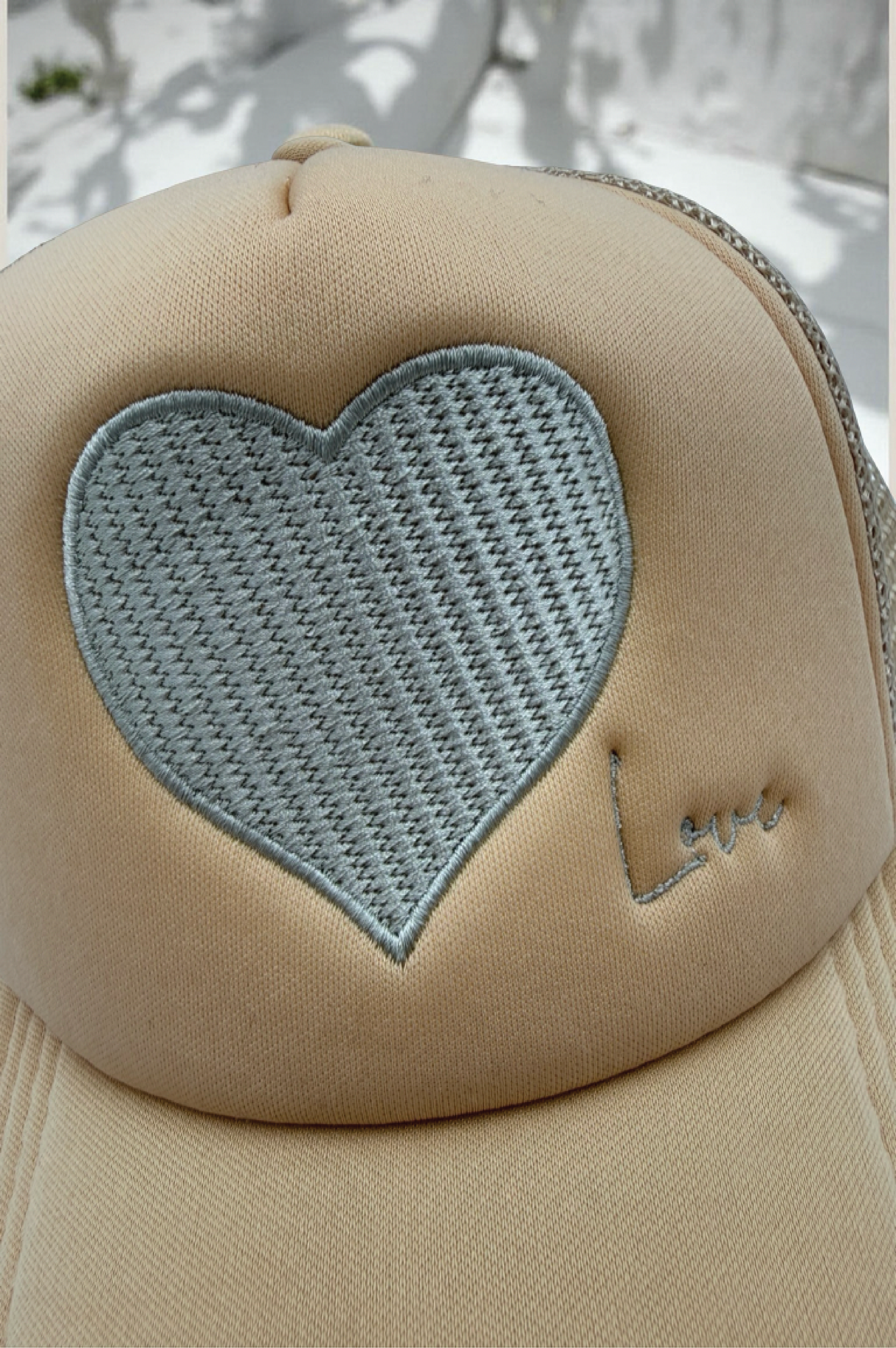 Beige cap with a heart-shaped patch and 'Love' embroidery on a light background