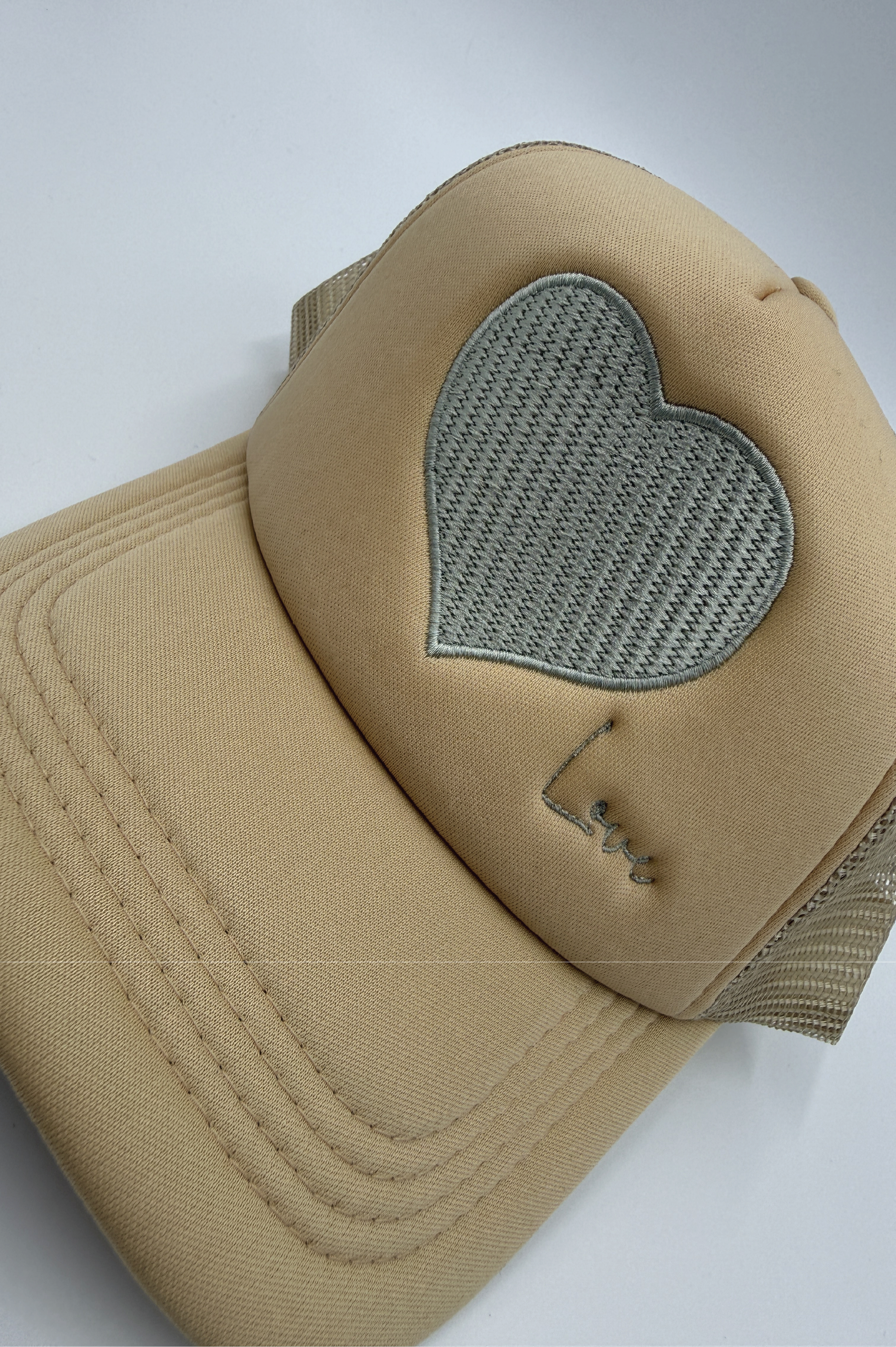 Beige cap with a heart-shaped mesh patch on a white background