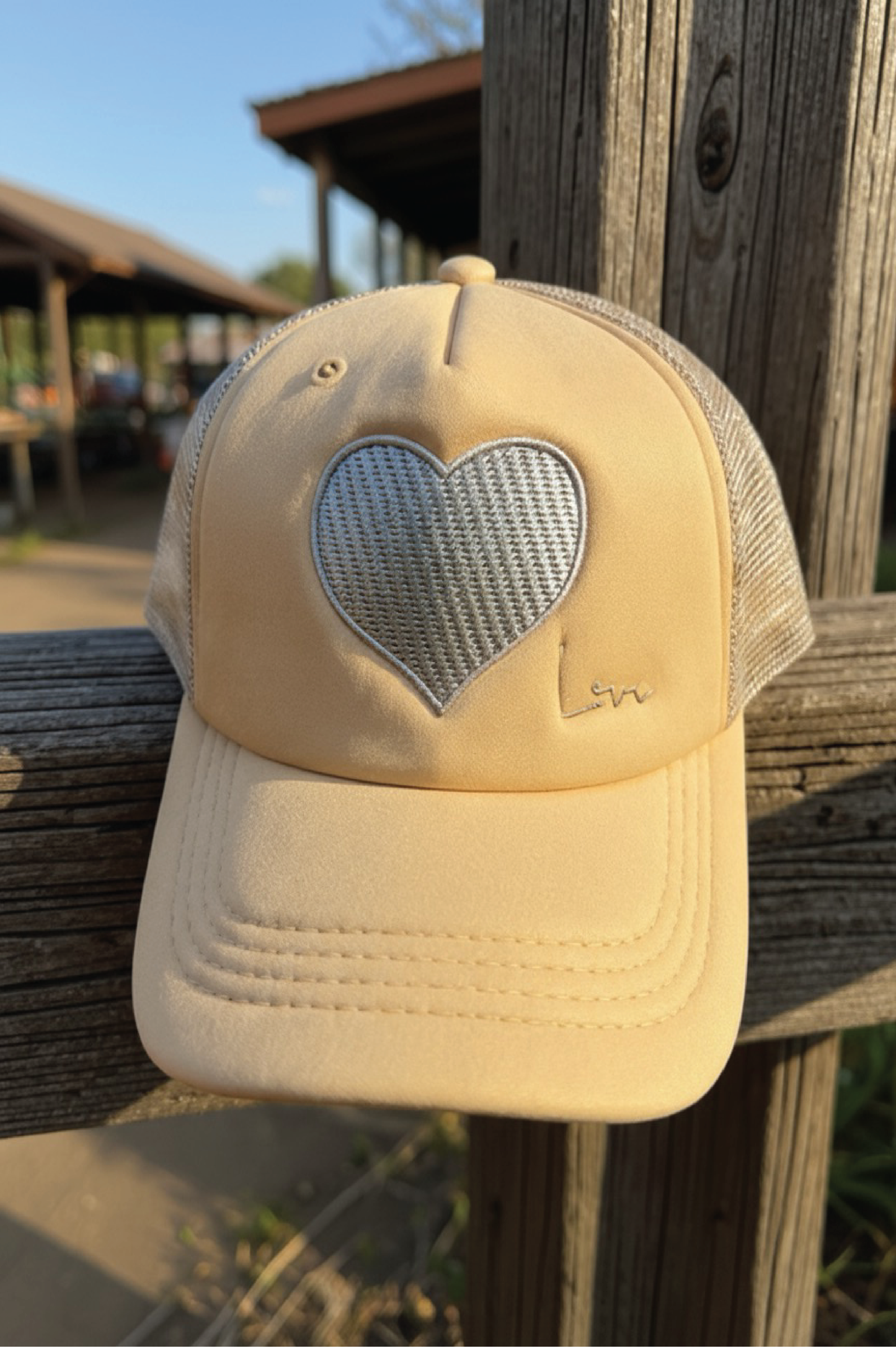 Beige cap with a heart-shaped mesh design on a wooden post outdoors